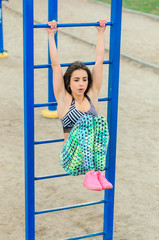 The girl the brunette to play sports on exercise machines. Exercise machines on the platform on the street