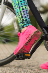 the girl the brunette in sportswear, rides a bike in the morning in the park. Close up a leg,