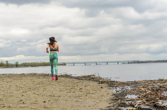 The girl the brunette plays sports on the seashore - on the beach.