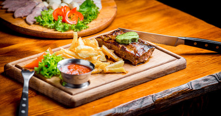 Beef steak with pepper sauce and Grilled vegetables on cutting board  dark wooden background
