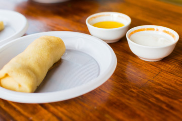 Pancake on a plastic plate. Honey and sour cream in the background