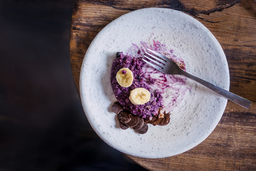 White empty plate with blueberry oatmeal dessert leftovers from above on wooden table. Dark food photography
