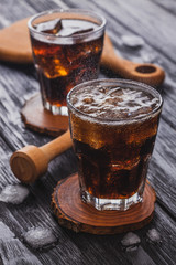 cola with ice in a glass on a black wooden table.
