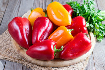 Red and yellow bell pepper on a cutting board on a wooden background
