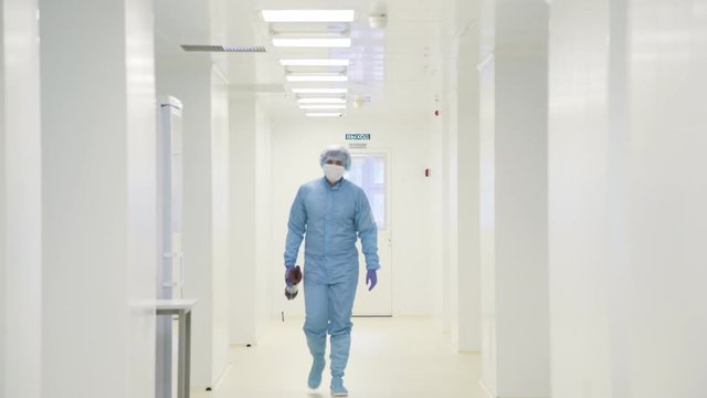 Two scientists in protective chemical suits and masks go in a sterile light laboratory room and meet in the corridor. Communication of colleagues in the scientific laboratory. Chemistry, biology.