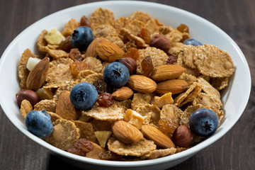 breakfast cereal with blueberries and nuts on a dark wooden table, closeup