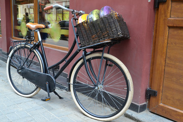 Fototapeta na wymiar bicycle with basket. Cheese in the basket. Cheese and bike on the street near the building. Old vintage bike