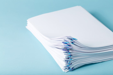 Pile of papers organized with paper clips on a blue background