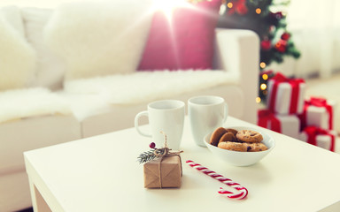 close up of gift, sweets and cups on table at home