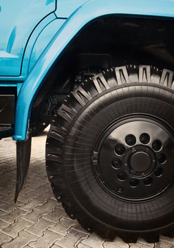 Big heavy truck wheel close-up. Black and blue tipper detail background