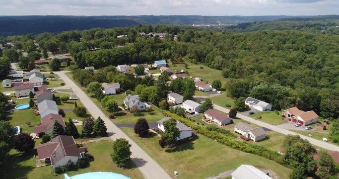 A daytime reverse aerial establishing shot of a typical Pennsylvania residential neighborhood with a large water tower in the foreground. Part 1 of 2.  	