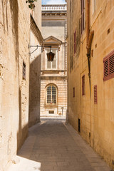 Fototapeta premium Wąska średniowieczna ulica z kamiennymi domami w Mdinie na Malcie
