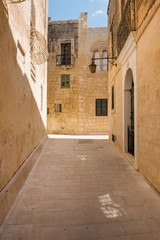 Fototapeta premium Narrow medieval street with stone houses in Mdina, Malta
