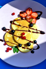 Ruddy pancake with berries in the bright rays of the morning sun.