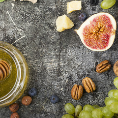 Cheese board for snacks, tricks, meetings with friends, on a gray stone background: assorted cheeses, young cheese, parmesan, cheese with fenugreek, figs, nuts, honey, grapes Top View.