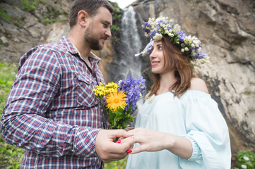 Hipster with a beard dresses an engagement ring of his beloved in the wild