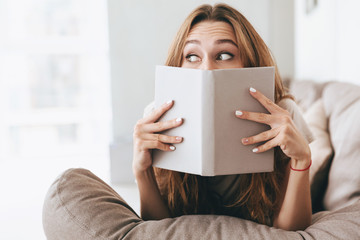 Pretty lady covering face with book.
