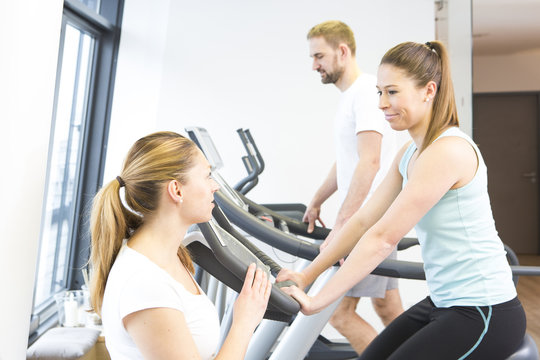 Physiotherapist helping patients with cycles in gym