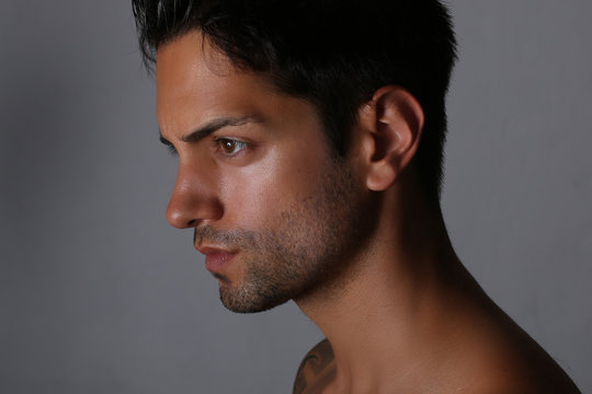 Side view portrait of an handsome man with nude torso over gray background