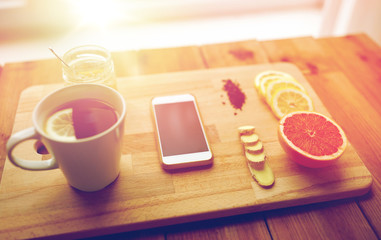 smartphone with cup of lemon tea, honey and ginger