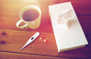 cup of tea, paper wipes and thermometer with pills