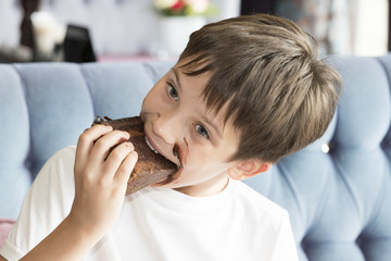 The boy is eating a large piece of cake in his hands 