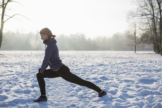 Young woman stretching in snow