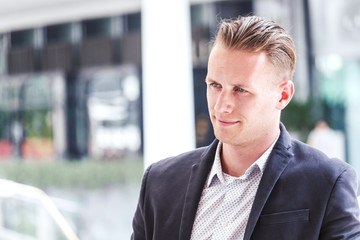 Portrait of handsome man in black suit standing outdoors