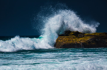 Powerful ocean wave breaking on the rock