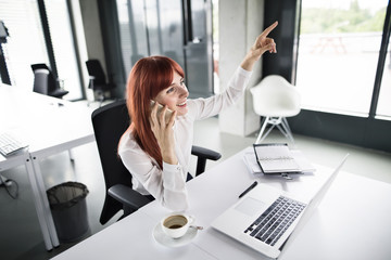 Businesswoman with smartphone and laptop in her office.