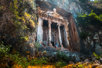 Amyntas rock tombs - 4th BC tombs carved in steep cliff. Tourist stands in front of the door. City of Fethiye, Turkey.