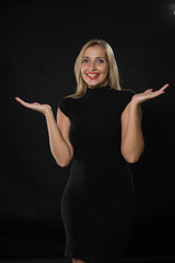 Young glad woman portrait of a confident businesswoman showing by hands on a black background. Ideal for banners, registration forms, presentation, landings, presenting concept