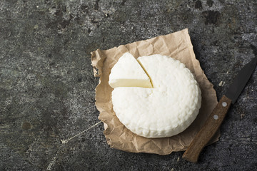 Young white cheese, a new recipe for cheese with fenugreek, a hard chopped Parmesan on a gray stone background with blueberries, nuts, green grapes, honey. Top view. Selective focus..