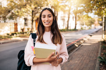 Female university student with book in campus - obrazy, fototapety, plakaty