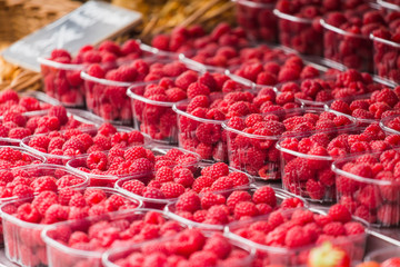 A lot of raspberries on the street market counter.