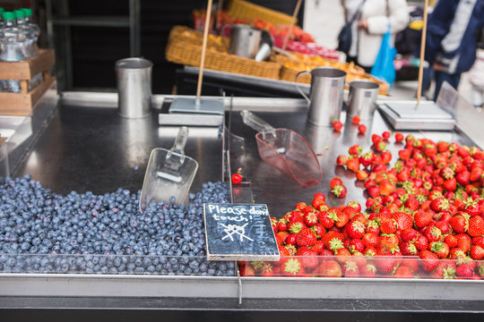 Strawberries, blueberries on the market counter. Traditional street market in Europe.