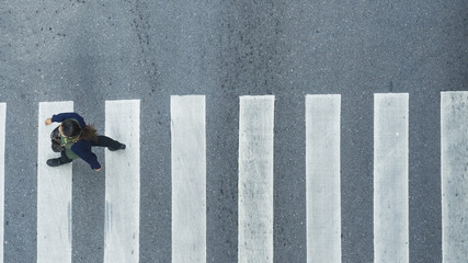 the top view of person walk across the pedestrian crosswalk in white and grey pattern
