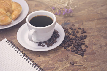 breakfast coffee and croissant with notepad put on wood background.
