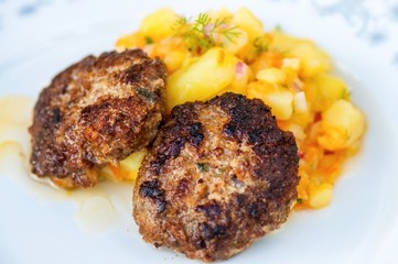 Two grilled burger with potato salad on plate.