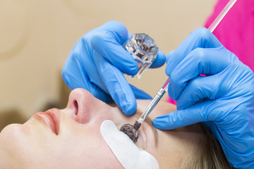Woman on the procedure for eyelash extensions, eyelashes lamination 