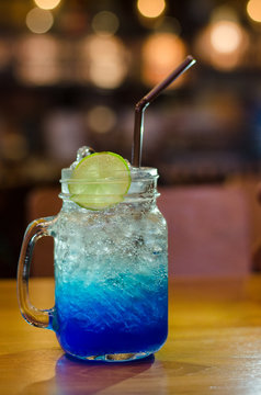Blue hawaiian soda with lemon on top on wood table (fresh drink soda)