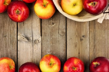 Freshly harvested apples with basket, double border on a rustic aged wood background