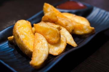 sweet potato fries with ketchup on black  plate over old wooden table.