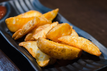 sweet potato fries with ketchup on black  plate over old wooden table.