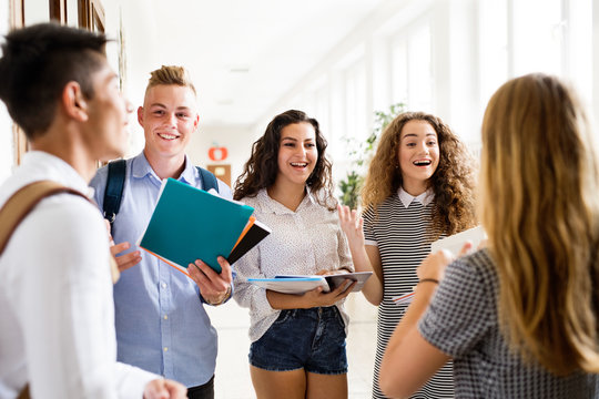 Teenage Students Walking In High School Hall, Talking.