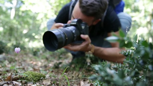 Giovane uomo fotografa le foto con un obiettivo macro in montagna