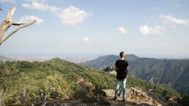 Giovane esploratore con maglia nera guarda il panorama dalla cima di una montagna