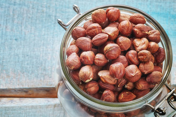 Obraz premium Hazelnuts in a jar on a rustic wooden background, space for text, shallow depth of field.