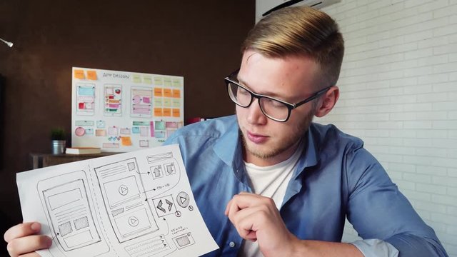 Young mobile app developer showing application prototype to his client using video conference