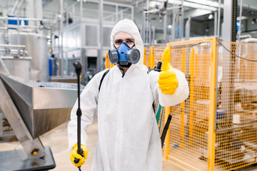 Fototapeta na wymiar Exterminator in industrial plant spraying pesticide with sprayer.